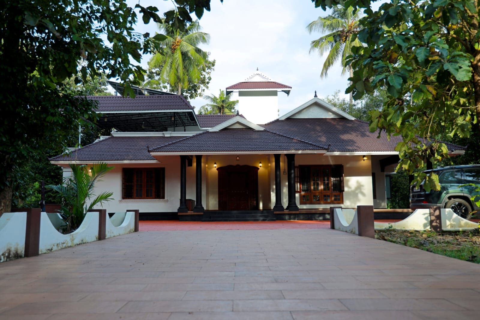 The full tiled-roof facade framed by coconut palms