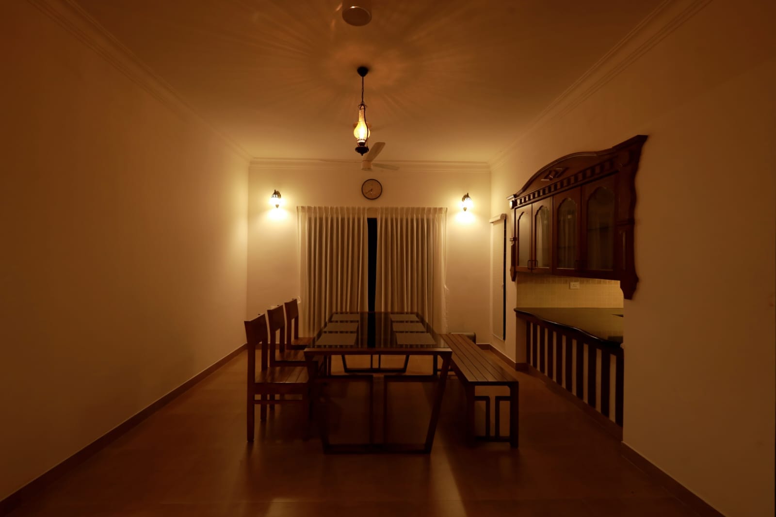 The long dining table set beneath a hanging brass lantern
